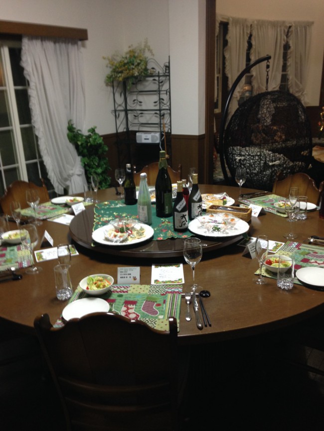 円形テーブルには６名のお食事をセッティングしました。中央には、様々なお酒があります。